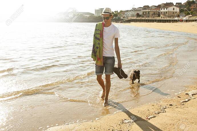 63358632-homme-qui-marche-avec-le-chien-sur-la-plage-soirée-d-été-lumière-douce