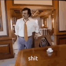 a man in a white shirt and tie is standing in front of a table with the word shit on it