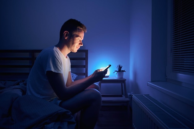 man-sitting-bedroom-using-phone-night_697241-318